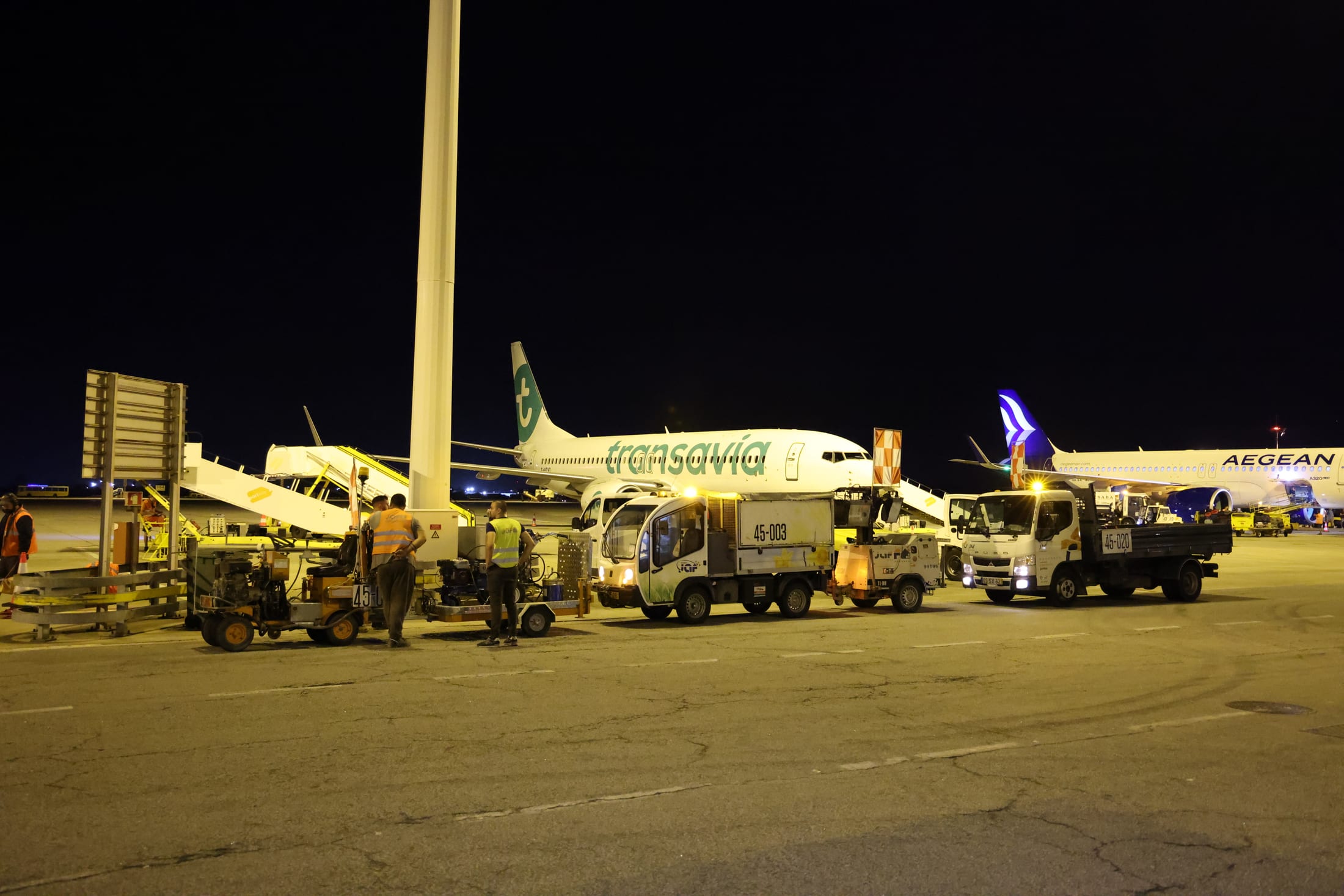 Placa aeroportuária à noite com aeronaves e equipamento