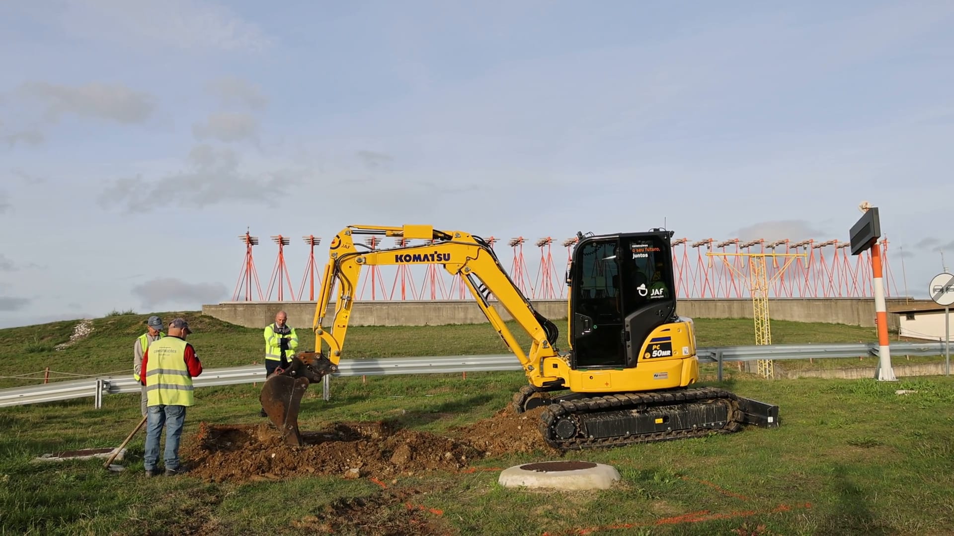 Escavadora da JAF em obra de infraestrutura aeroportuária, junto às luzes de aproximação
